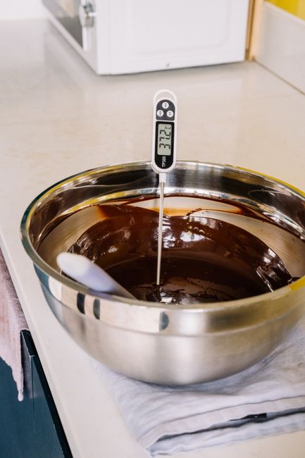 A thermometer in a bowl of melted chocolate.